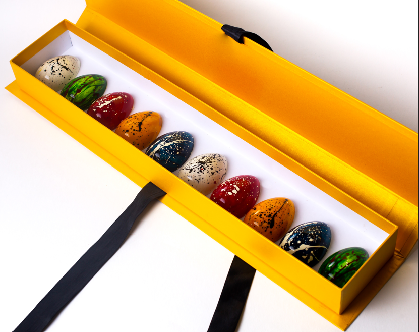 Stylized egg-shaped chocolates in yellow box, showcasing artistic design and gourmet appeal.