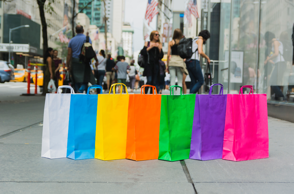 Colorful eco-friendly paper shopping bags lined up on a busy city street, symbolizing sustainable packaging and modern retail marketing