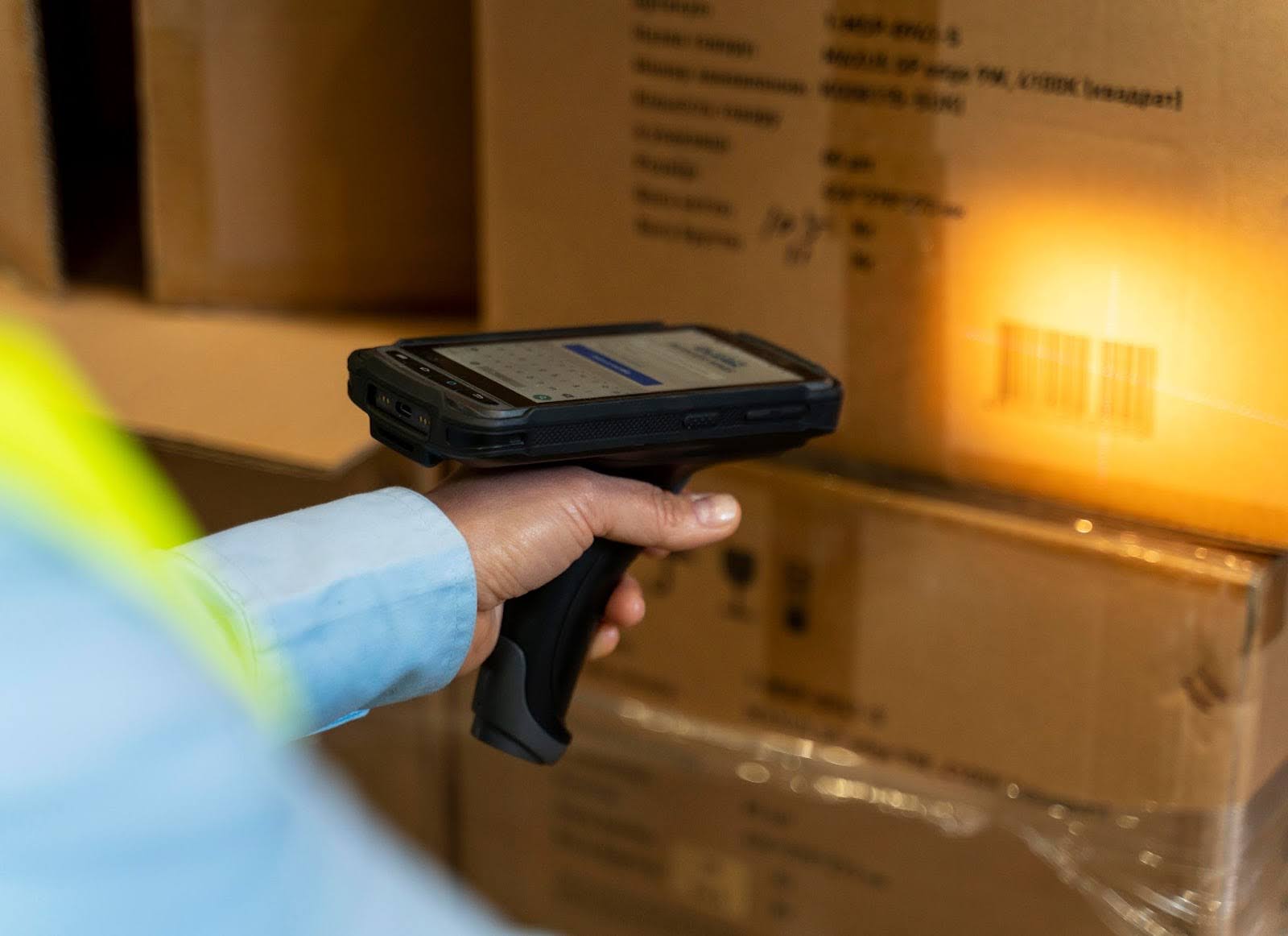 Close-up of warehouse worker scanning a barcode on cardboard packaging box with handheld scanner for inventory and logistics management