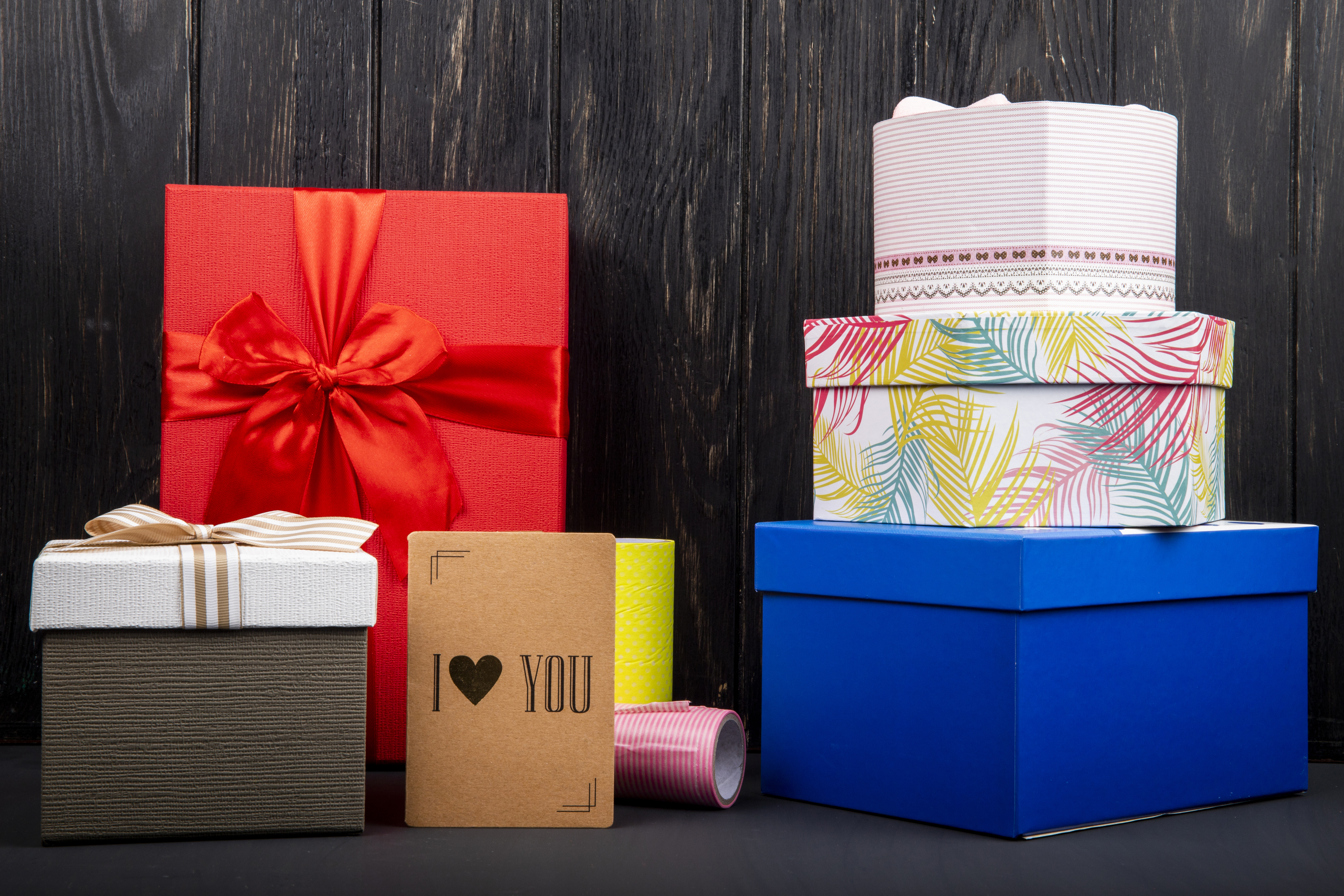 Pyramid display of 2025 celebration gift packaging trends featuring a variety of eco-friendly green boxes alongside brown, blue, and red wraps with minimalist designs